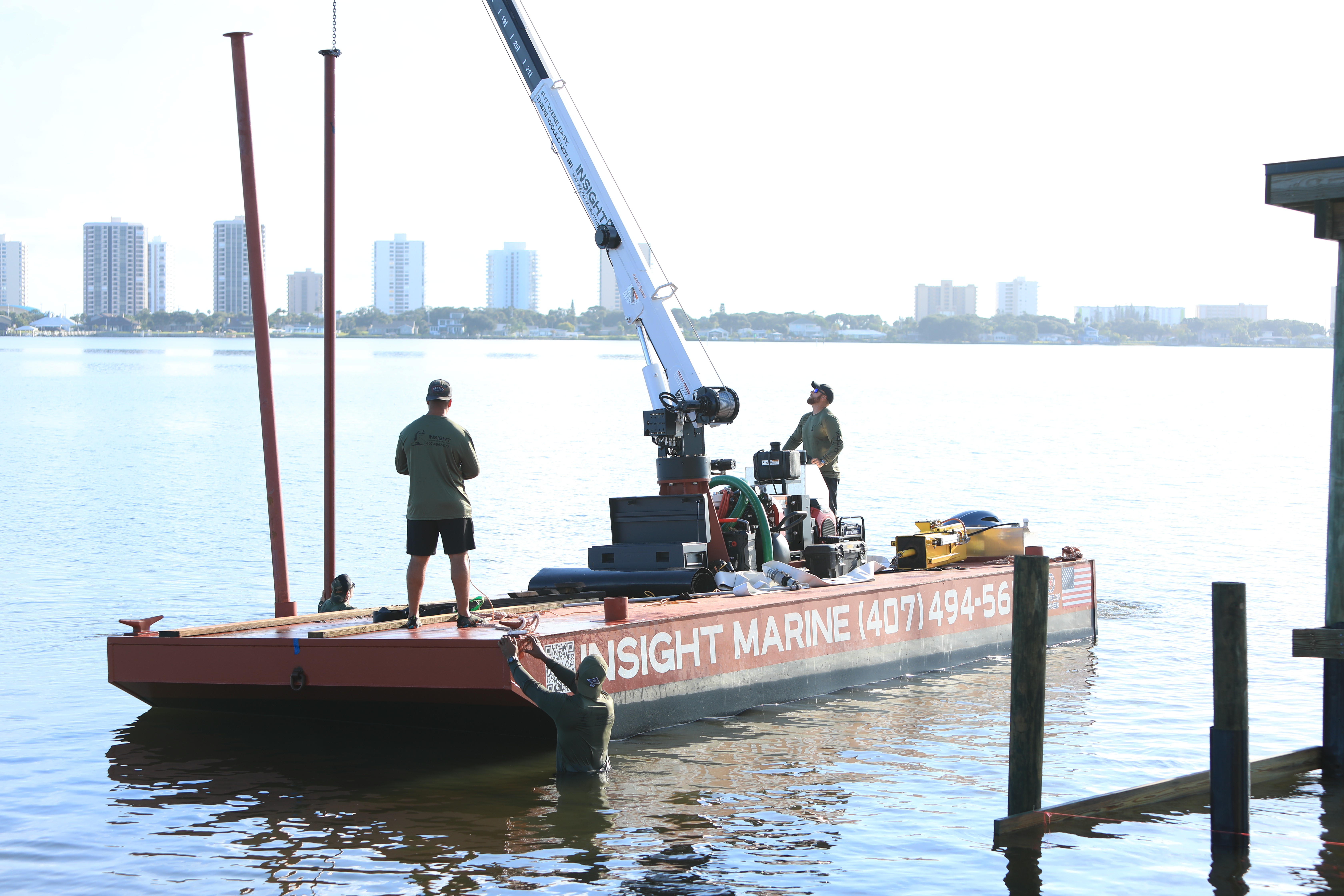 Insight Marine barge with piles standing and the crew working the crane