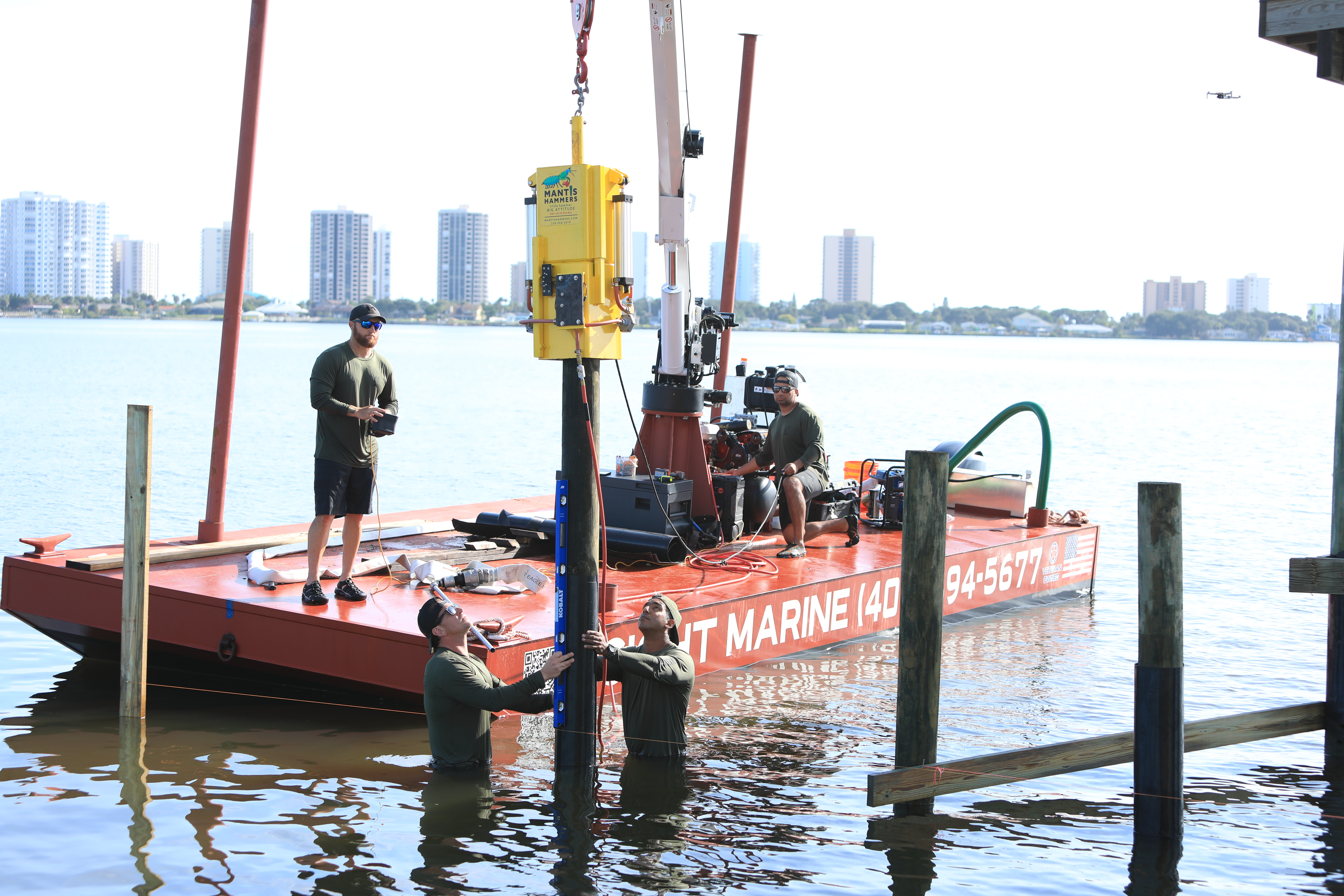 Two crew members holding a level on a pile while the hammer sets it