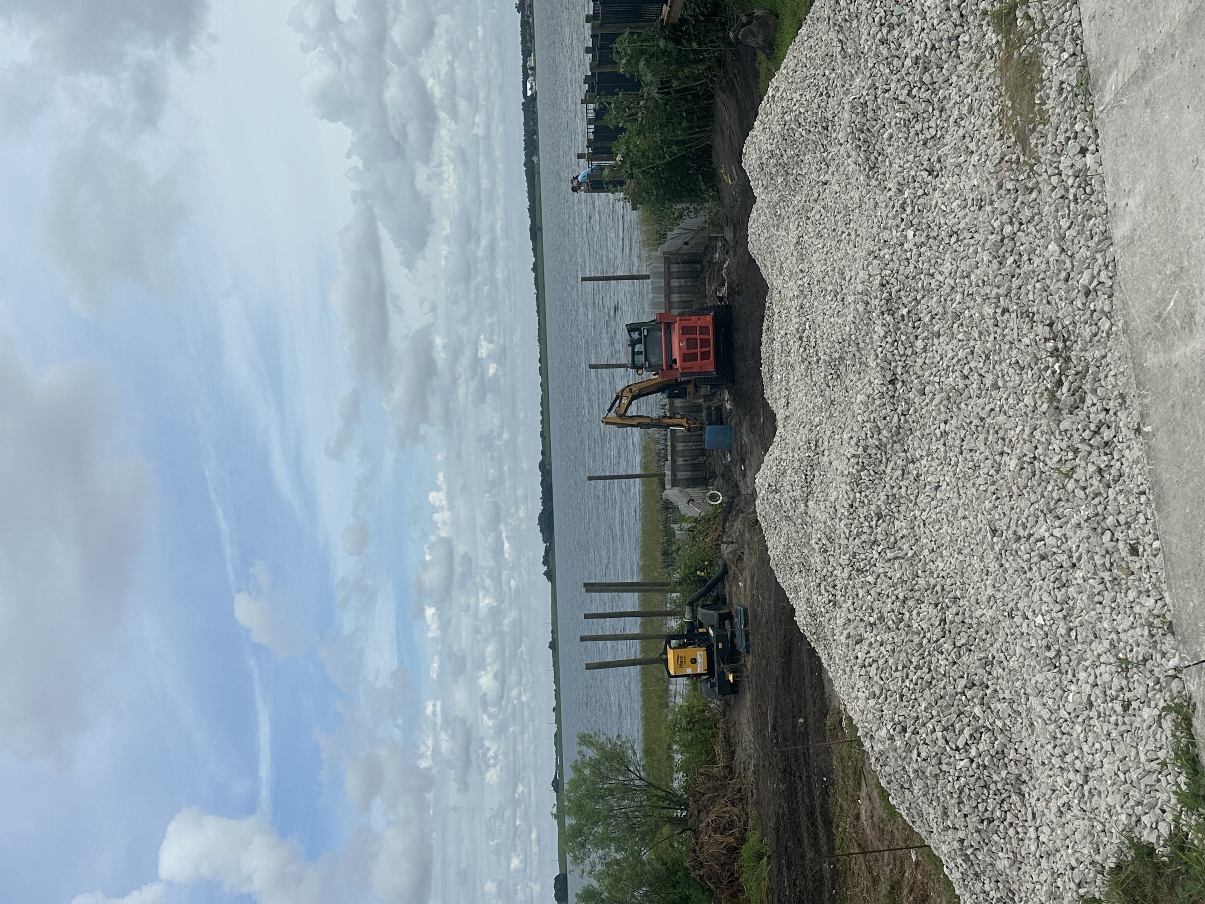 Sheet pile seawall going in along a lakefront with an excavator on the bank